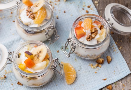 Healthy breakfast overnight oats with fresh fruit in a glass jar on wooden backgroundの写真素材