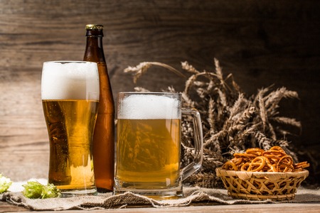Mug, glasse, bottle of beer with foam close up with hop, pretzels and wheatの写真素材