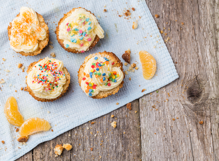 Cupcakes with white frosting and sprinkles on wooden backgroundの写真素材