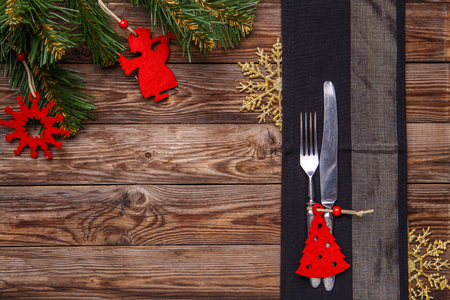 Christmas table place setting with fork and knife, decorated christmas toy, gold snowflakes and christmas pine branches. Christmas holidays background.の写真素材