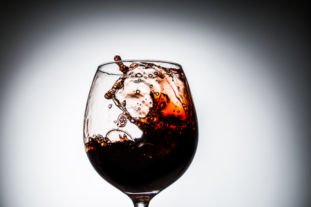 Stream of wine being pouring into a glass. Closeup splash of wine.の写真素材