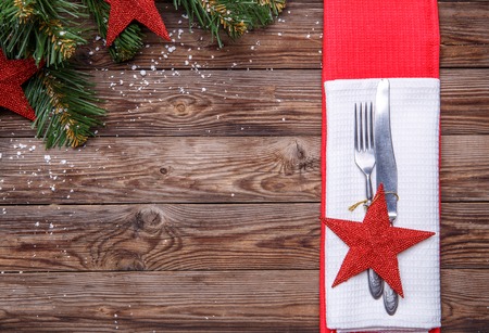 Christmas table place setting with fork and knife, decorated red star, white napkin and christmas pine branches with toys. Christmas holidays background.の写真素材
