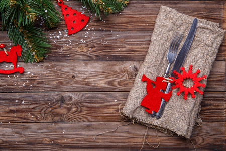 Christmas table place setting with fork and knife, decorated red christmas toys, sackcloth napkin and christmas pine branches. Christmas holidays background.の写真素材
