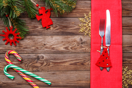 Christmas table place setting with fork and knife, decorated christmas toy - red fir-tree, christmas pine branches and two lollipop cane. Christmas holidays background.の写真素材
