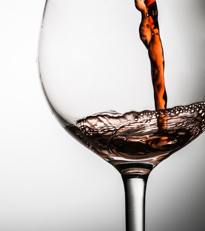 Red wine poured into glass standing on empty gray backgroundの写真素材