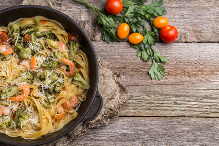 Pasta linguine with shrimps and broccoli in dripping pan on wooden background. Flat lay.の写真素材