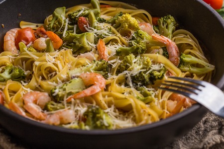 Pasta linguine with shrimps and broccoli in dripping pan on wooden background. Top view.の写真素材