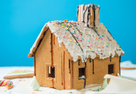 Homemade gingerbread house with glaze and confectionery sprinkling on blue backgroundの写真素材