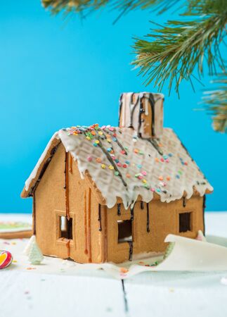 Homemade gingerbread house with fir-tree brunch on blue background.の写真素材