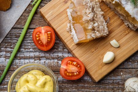 Homemade jelly meat with mustard, bread, tomatoes and garlic on the table. Holodets