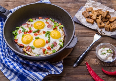 Fried eggs in pan with tomatoes and green fresh onion.の写真素材