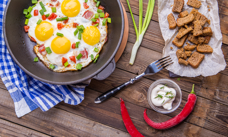 Fried eggs in pan with tomatoes and green fresh onion.の写真素材