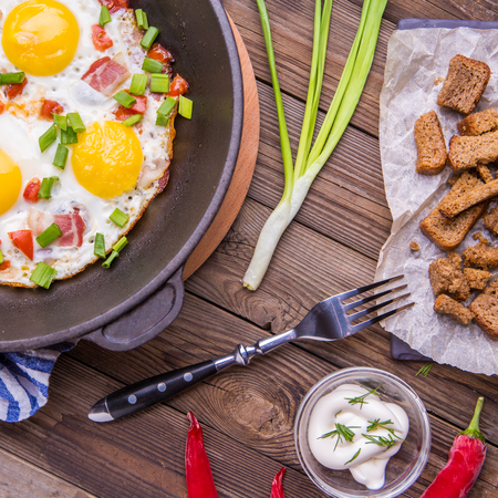 Fried eggs in pan with tomatoes and green fresh onion.の写真素材