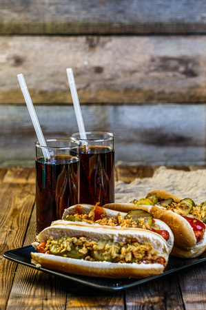 American hot dog with pickles,onions, ketchup, mustard and two sodaの写真素材