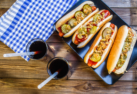 American hot dog with pickles,onions, ketchup, mustard and two sodaの写真素材