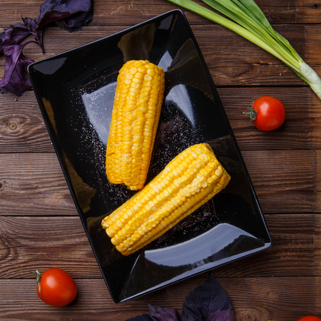 Corn on the black plate on wooden tableの写真素材