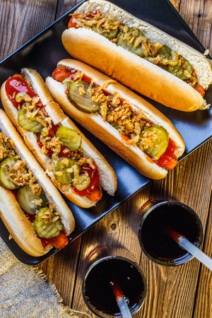 American hot dog with pickles,onions, ketchup, mustard and two sodaの写真素材