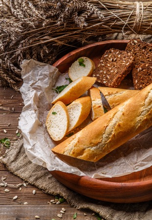 Long loaf , bread with cereals on wooden plate on table with sackcloth clothの写真素材