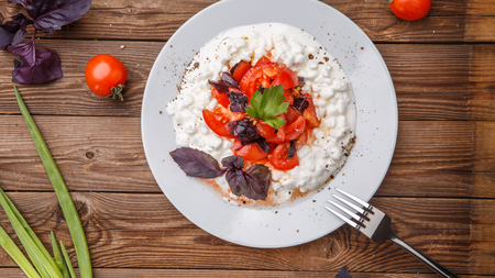 Salad with cottage cheese and tomatoes on wood table.の写真素材