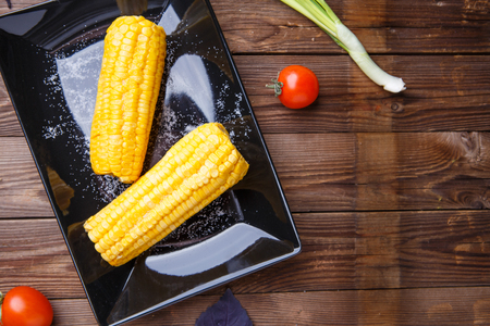 Corn on the black plate on wooden tableの写真素材