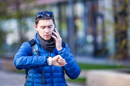 Man talking on phone and looking at smartwatchの写真素材