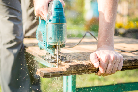 Man with electric jigsaw worksの写真素材