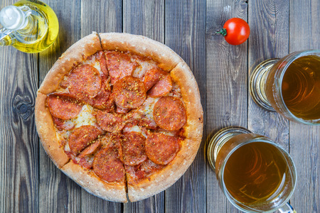 Pizza with two glasses beer on brown wooden table.の写真素材