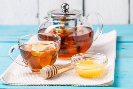 Glass cup of tea with lemon, glass teapot and honey.の写真素材