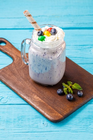 Fresh blueberries milkshake and berries on wooden desk on blue table.の写真素材