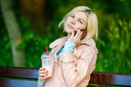 Girl with milkshake and phoneの写真素材