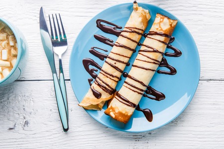 Homemade pancakes or russian blini with chocolate sauce on plate on white wooden background.の写真素材