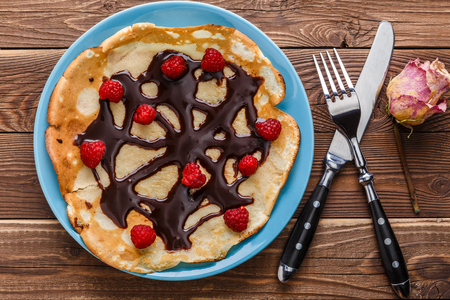 Photo of round pancakes on plate of chocolate, with berriesの写真素材