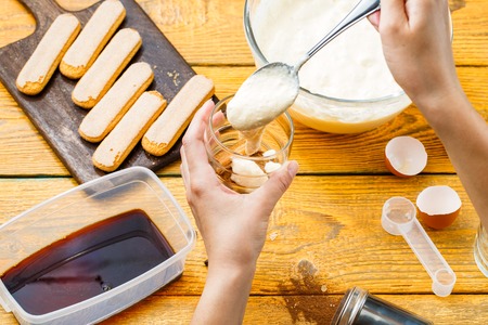 Photo of cooking tiramisu, human hands with spoon
