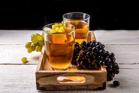 Image of wooden box with two glasses of wine, black and green grapesの写真素材