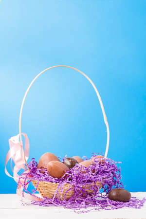 Image of chicken, chocolate eggs, purple decorative paper in basket