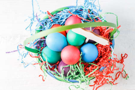 Image on top of basket with colorful eggs on wooden table