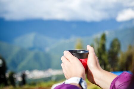 Photo of womans hands with cup on blurred background of autumnal parkの写真素材