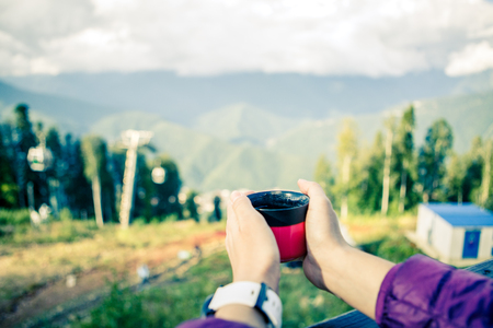 Photo of womans hands with cup on blurred background of autumnal parkの写真素材