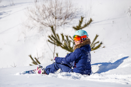 Photo of athlete in helmet with snowboard sitting at fir -treeの写真素材