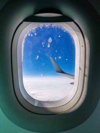 Photo of porthole with view to wing of airplaneの写真素材
