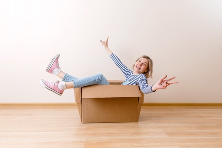Photo of young woman sitting in cardboard box