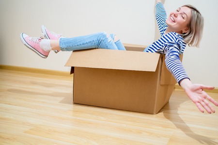 Photo of young blond woman sitting in cardboard boxの写真素材