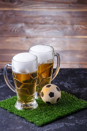 Photo of two beer mugs, green grass with soccer ballの写真素材