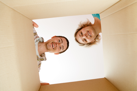 Photo of man and woman peering into cardboard boxの写真素材
