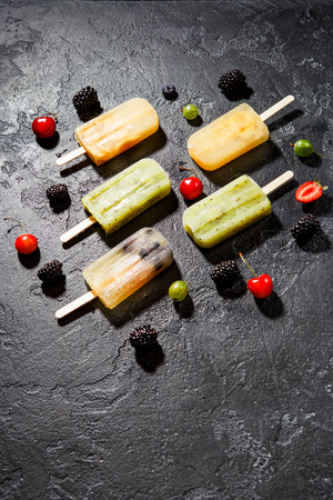 Photo of frozen juice on stick, blackberry,cherry, gooseberriesの写真素材