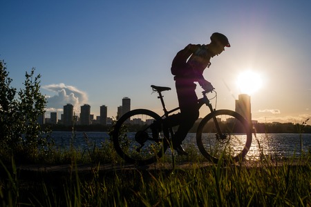 Photo of bicyclist wearing helmet riding around city in eveningの写真素材