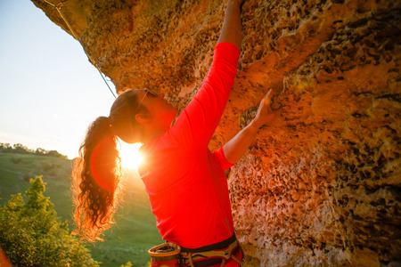 Image of young brunette tourist hiking over rock on summer day.