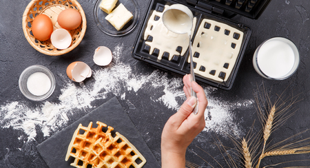 Photo on top of flour, eggs, waffle iron, spikelets, fresh roasted waffles, human handsの写真素材