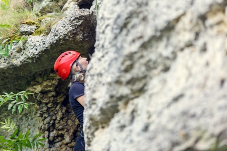 Photo of tourist woman in red helmet climbing on rockの写真素材