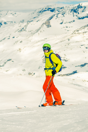 Photo of sportive man skiing against background of snowy mountainsの写真素材